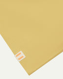 Hem close-up of the sandstone organic cotton T-shirt showing texture of the medium weight organic cotton jersey and the small square Uskees branding tag.