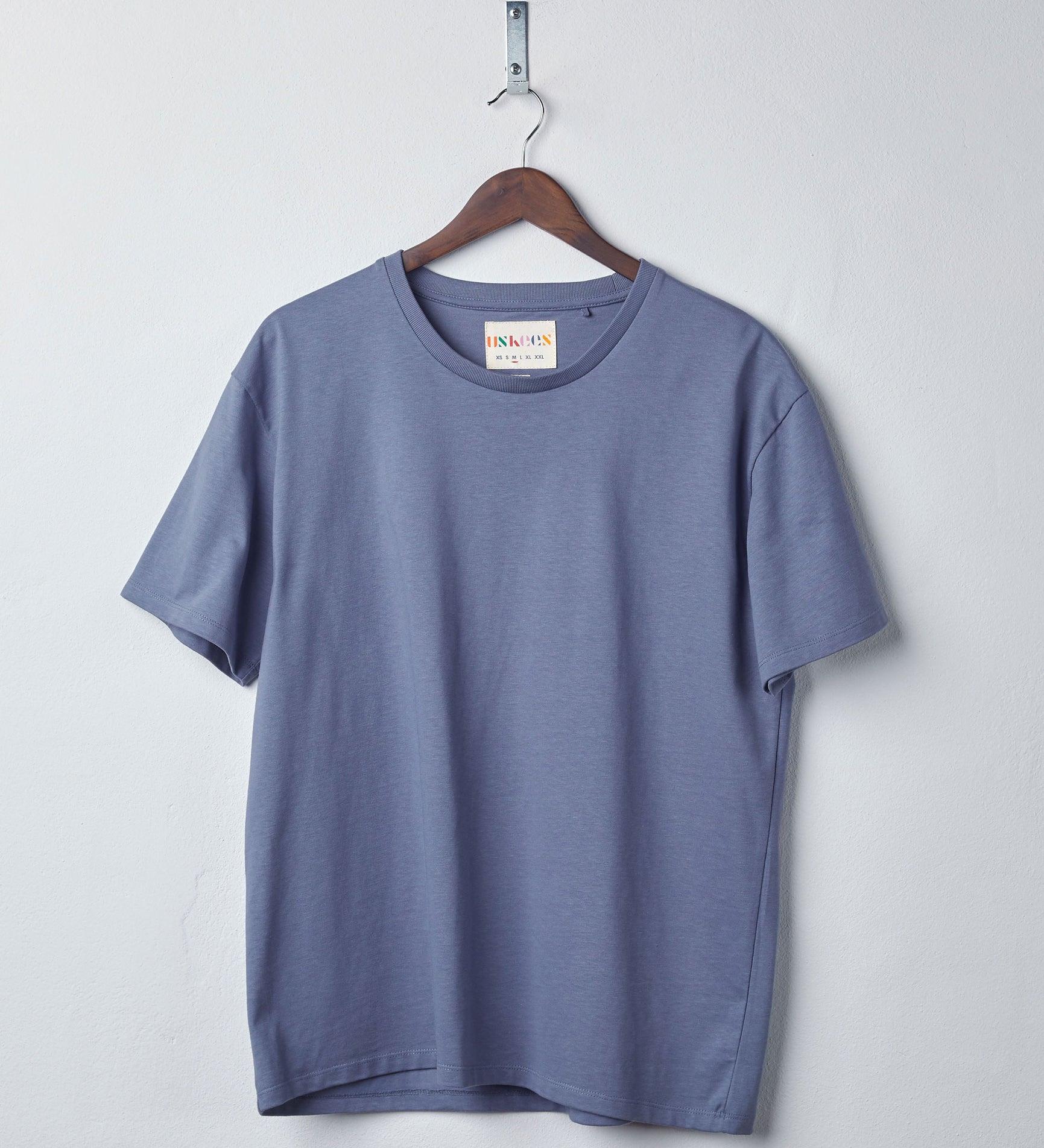 Front view of teal organic cotton #7006 jersey T-shirt by Uskees, presented on hanger against white background. 