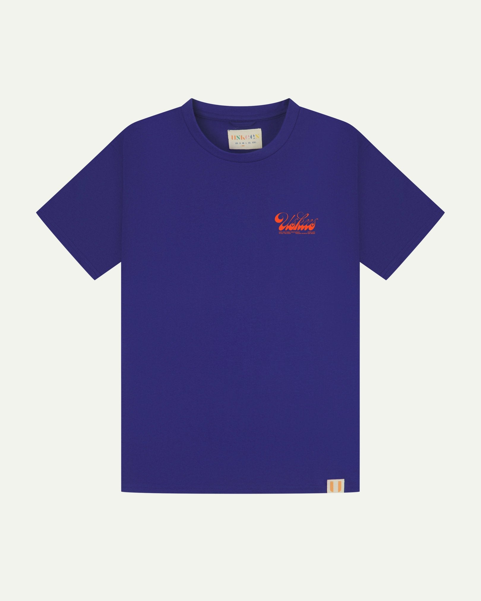 Full flat view of ultra blue organic cotton Uskees T-shirt for men, showing the small bright orange 'diner' logo on the breast.