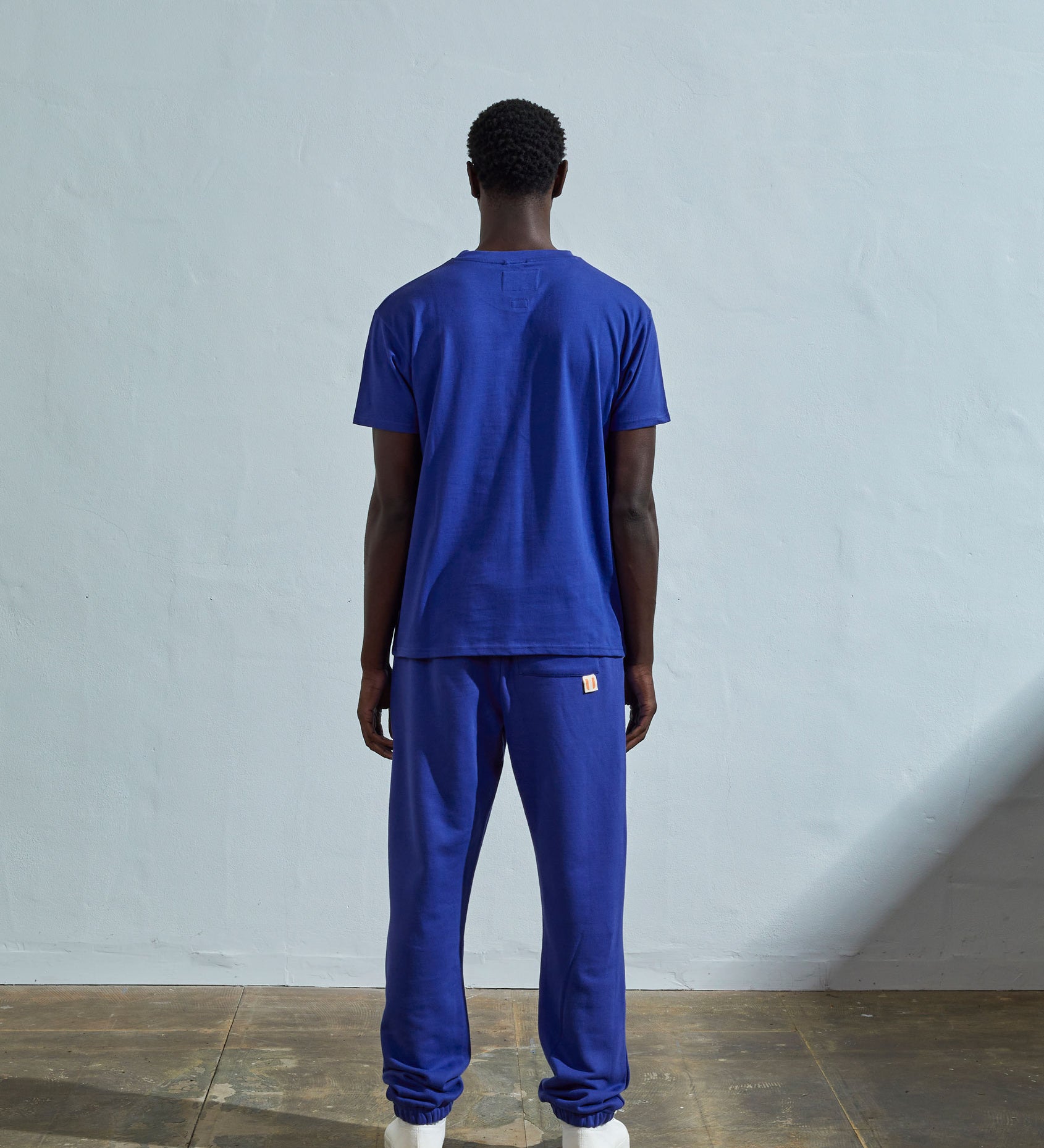 Full-length back view of model wearing ultra blue, relaxed cut organic cotton #7006 jersey T-shirt by Uskees paired with matching pants.