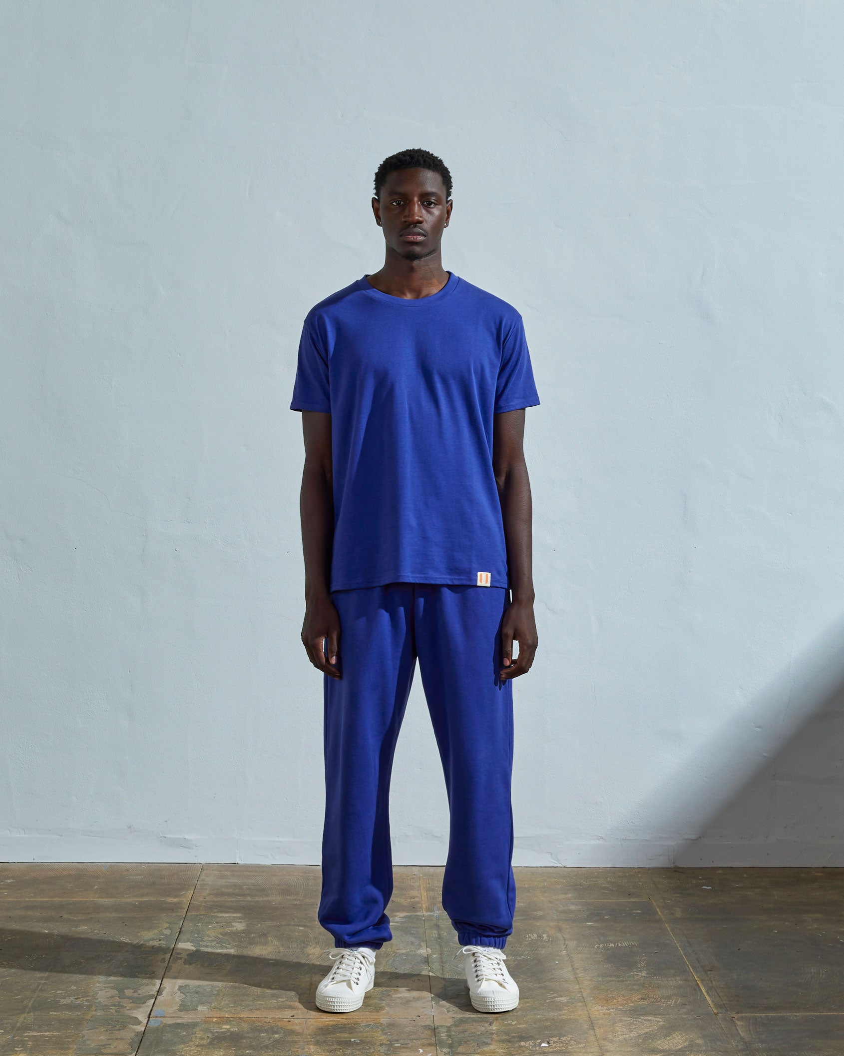 Full-length front view of model wearing ultra blue organic cotton #7006 jersey T-shirt by Uskees paired with matching pants.