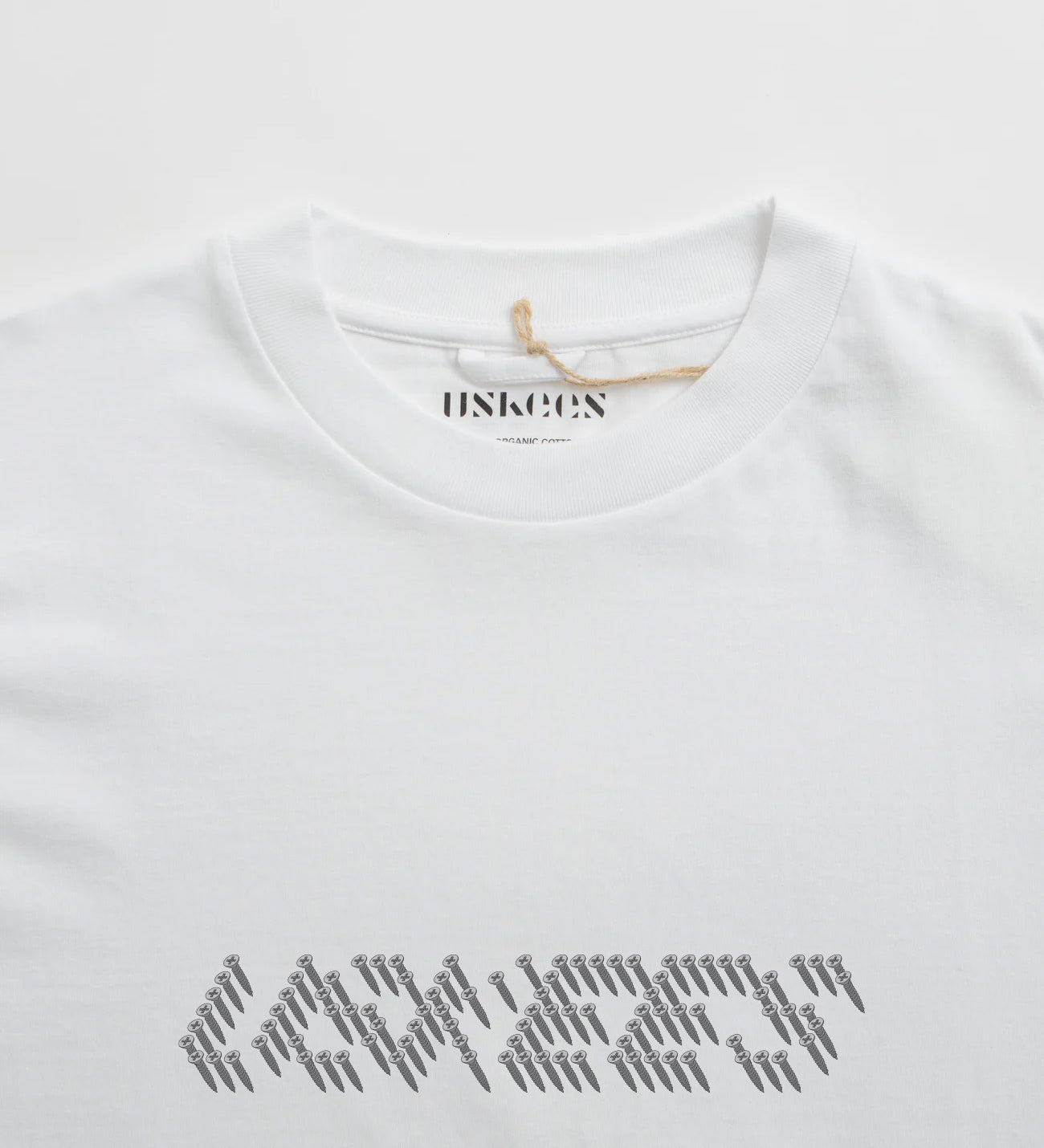 Close-up neckline view of Uskees men's graphic t-shirt in white showing the philips head screw graphic and the texture of the enzyme washed, organic cotton jersey material.