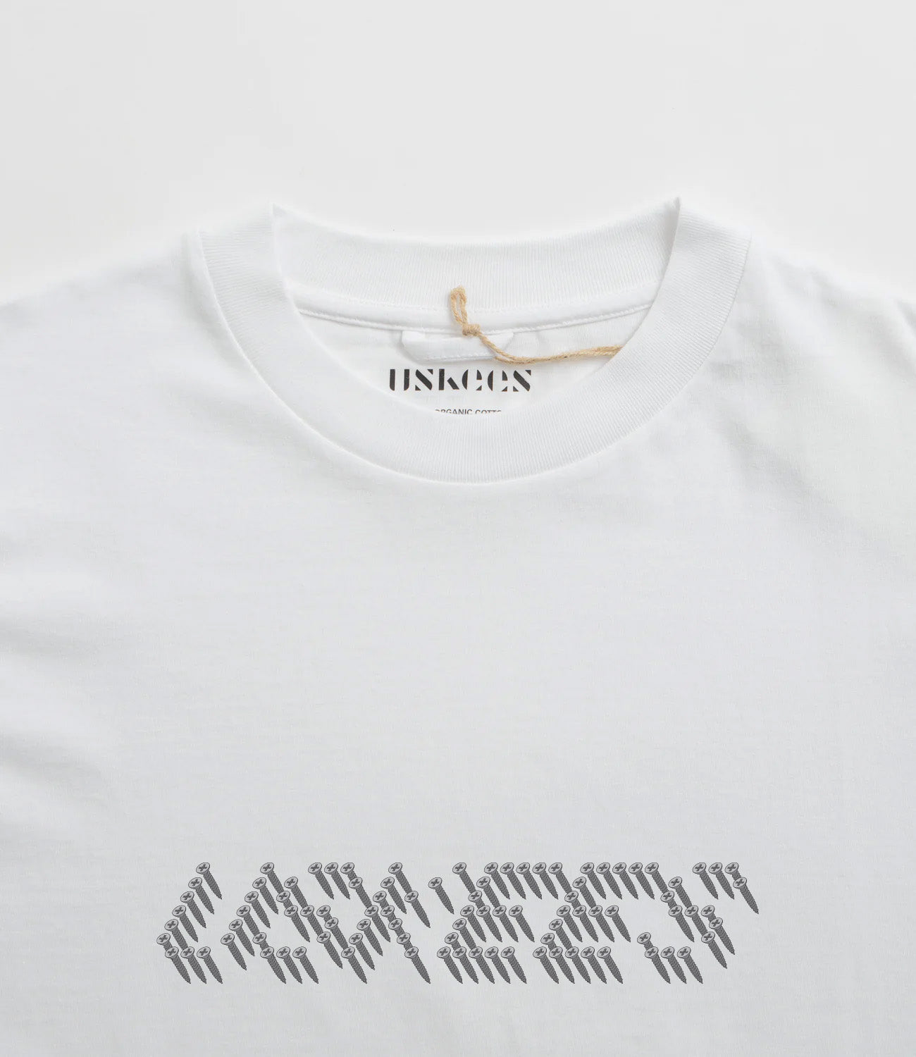 Close-up neckline view of Uskees men's graphic t-shirt in white showing the philips head screw graphic and the texture of the enzyme washed, organic cotton jersey material.