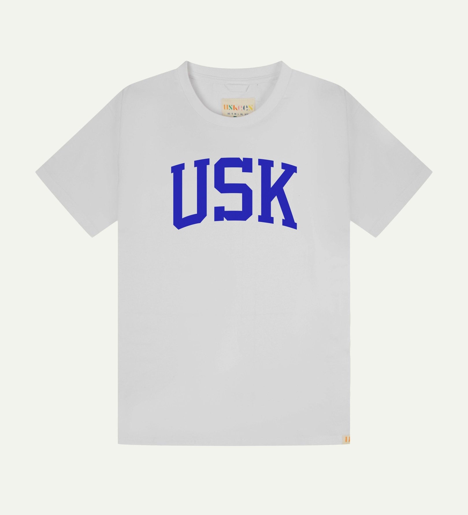 Full flat view of white organic cotton signature T-shirt for men, showing the varsity inspired 'USK' logo in blue on the chest, and the Uskees branding labels on the neck and hem.