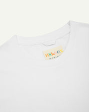 Neckline close-up of Uskees white organic cotton T-shirt showing hanging loop and branding label.