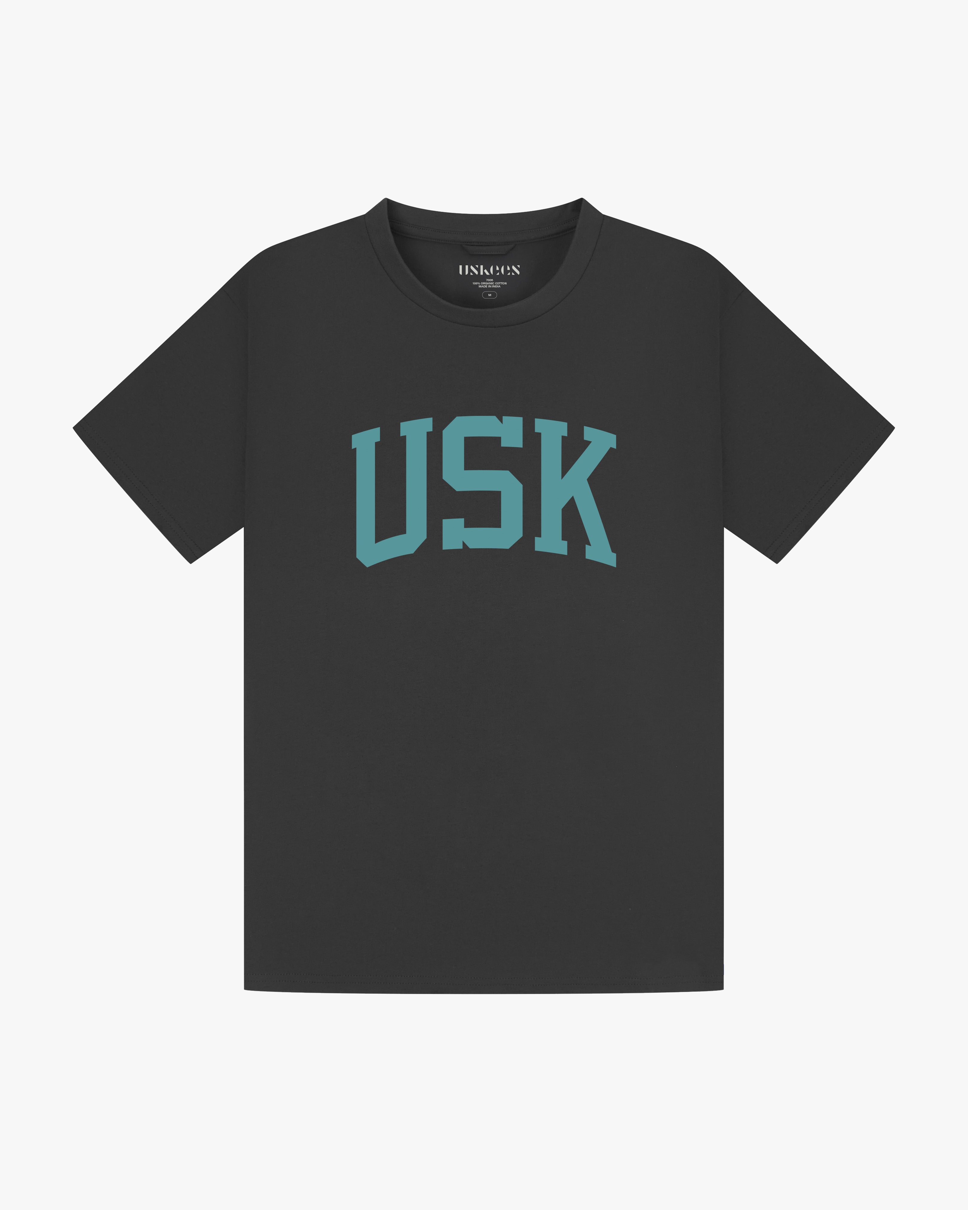 Full flat view of faded black organic cotton signature T-shirt for men, showing the varsity inspired 'USK' logo on the chest and the Uskees branding labels on the neck and hem.