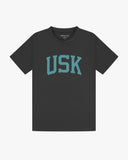 Full flat view of faded black organic cotton signature T-shirt for men, showing the varsity inspired 'USK' logo on the chest and the Uskees branding labels on the neck and hem.
