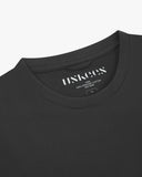 Neckline close-up of Uskees faded black organic cotton T-shirt showing hanging loop and branding label.