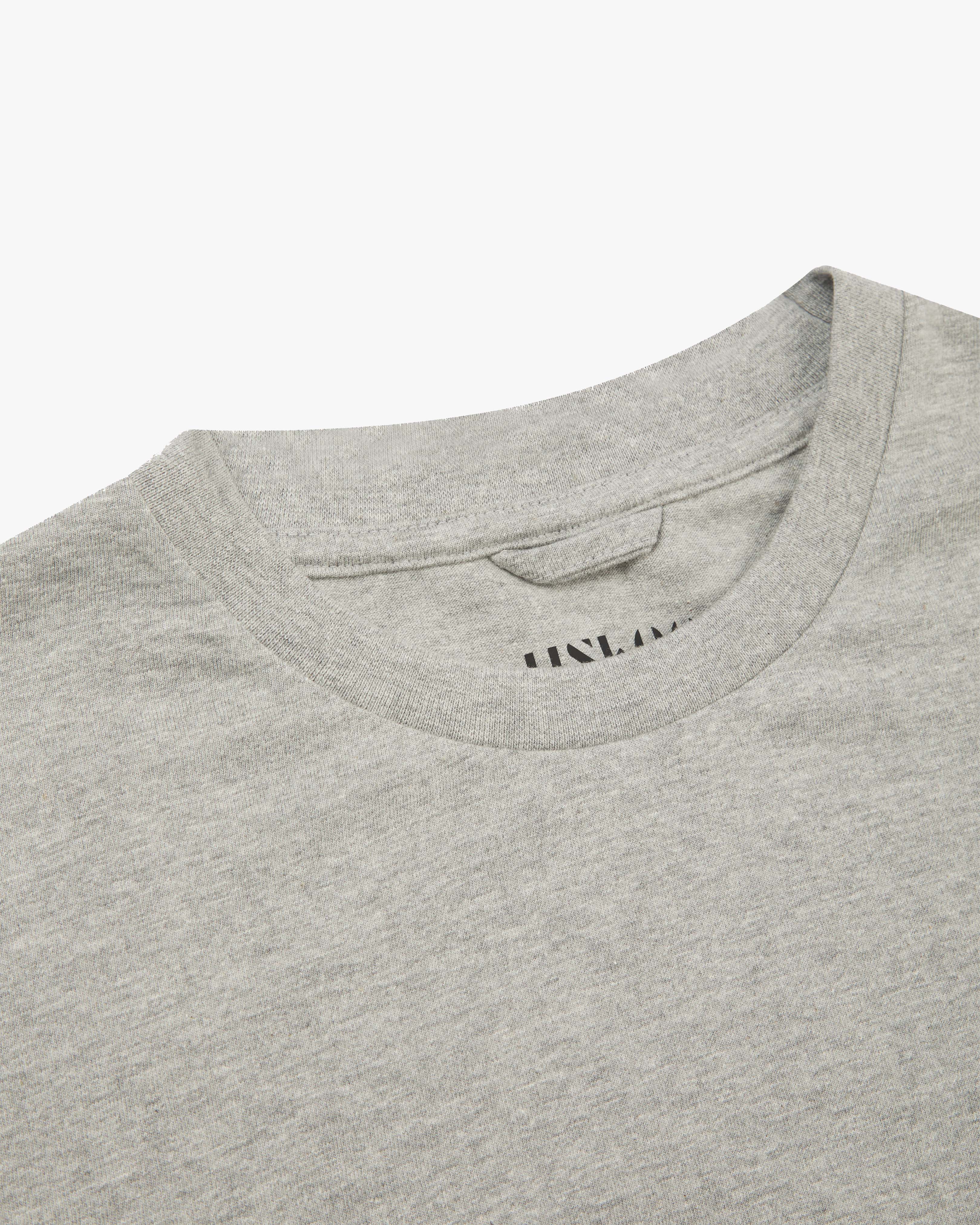 Neckline close-up of Uskees grey marl organic cotton T-shirt showing hanging loop and branding stamp.