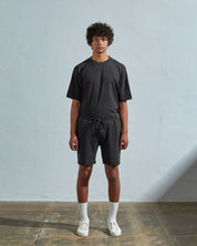 Front view of model wearing faded black, relaxed cut organic cotton #7007 jersey shorts by Uskees with focus on drawstring and loose fit.