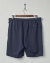 Back view of midnight blue organic cotton #7007 jersey shorts by Uskees. Presented on hanger against white background. Clear view of back pocket with corozo button.
