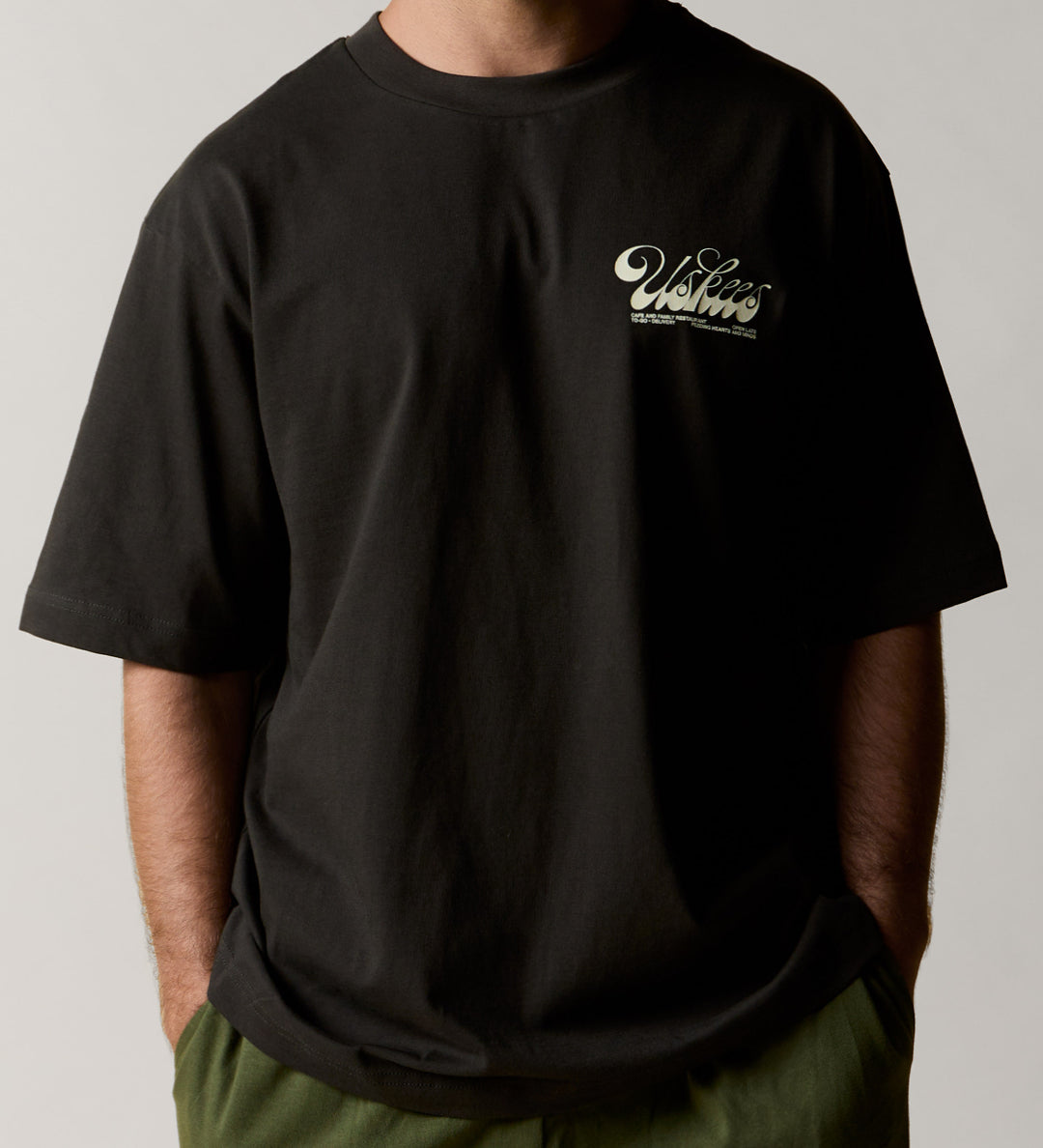 Front view wearing the uskees men's 'diner' tee in black demonstrating the loose, oversized fit.