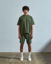 Full-length front view of model wearing coriander-green organic cotton #7008 oversized jersey T-shirt by Uskees paired with matching shorts.