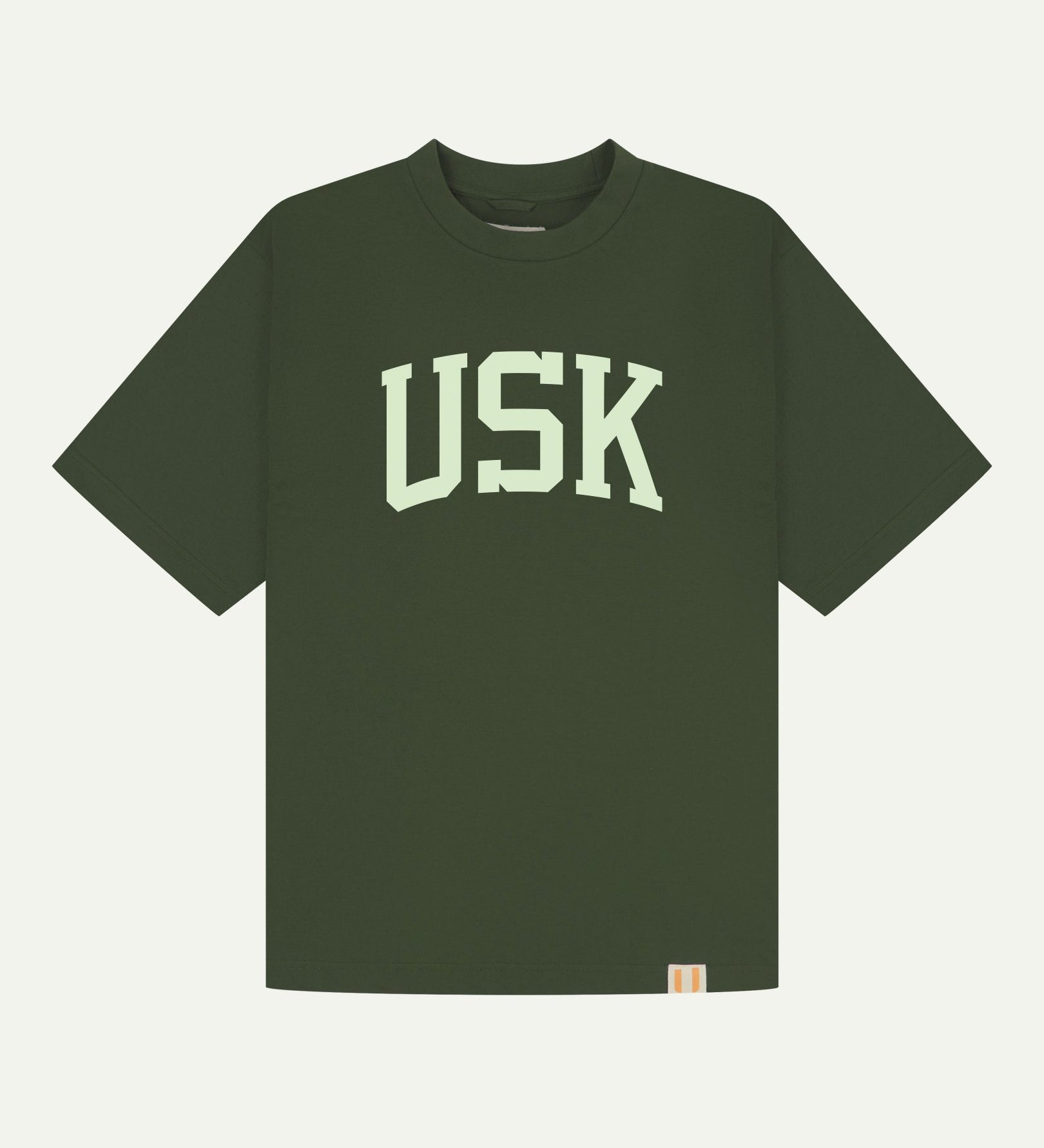 Full flat view of oversized coriander-green organic cotton signature T-shirt for men, showing the varsity inspired 'USK' logo on the chest and the Uskees branding labels on the neck and hem.