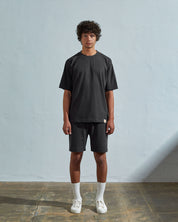 Full-length front view of model wearing faded black organic cotton #7008 oversized jersey T-shirt by Uskees paired with matching shorts.