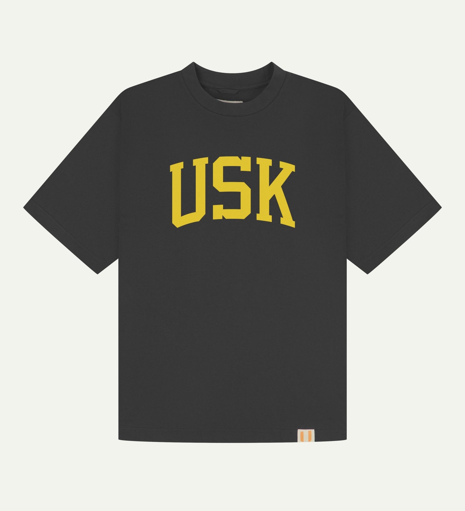 Full flat view of oversized faded black organic cotton signature T-shirt for men, showing the varsity inspired 'USK' logo in yellow on the chest, and the Uskees branding labels on the neck and hem.