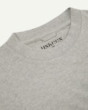 Neckline close-up of the oversized Uskees grey-marl organic cotton T-shirt showing hanging loop and branding stamp.