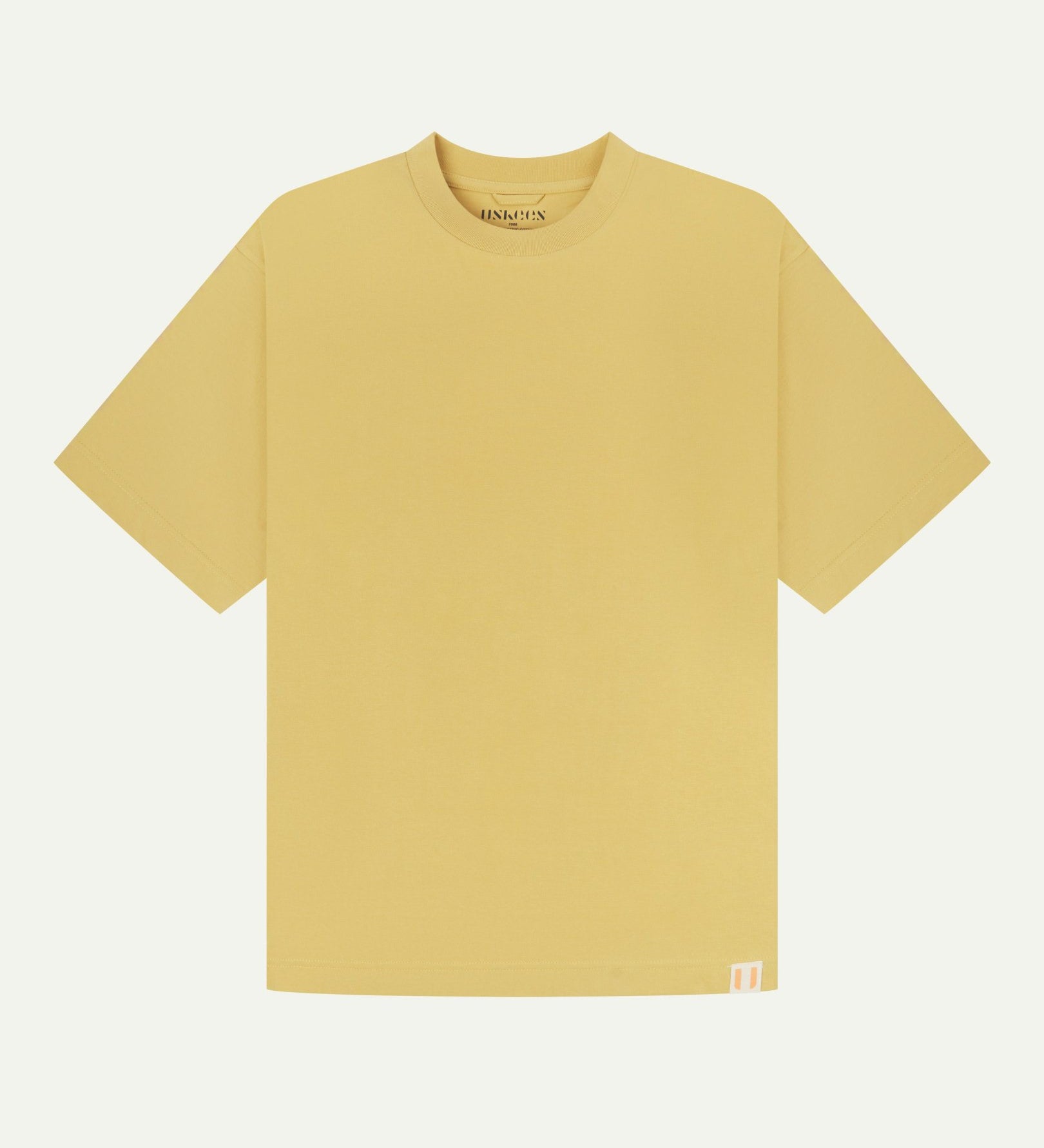 Full flat view of sandstone-yellow organic cotton Uskees T-shirt for men, showing the looser, oversized silhouette.