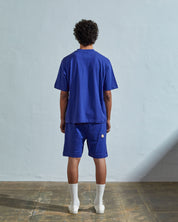 Full-length back view of model wearing ultra blue, relaxed cut organic cotton 7008 oversized jersey T-shirt by Uskees paired with matching shorts.