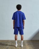 Full-length back view of model wearing ultra blue, relaxed cut organic cotton 7008 oversized jersey T-shirt by Uskees paired with matching shorts.