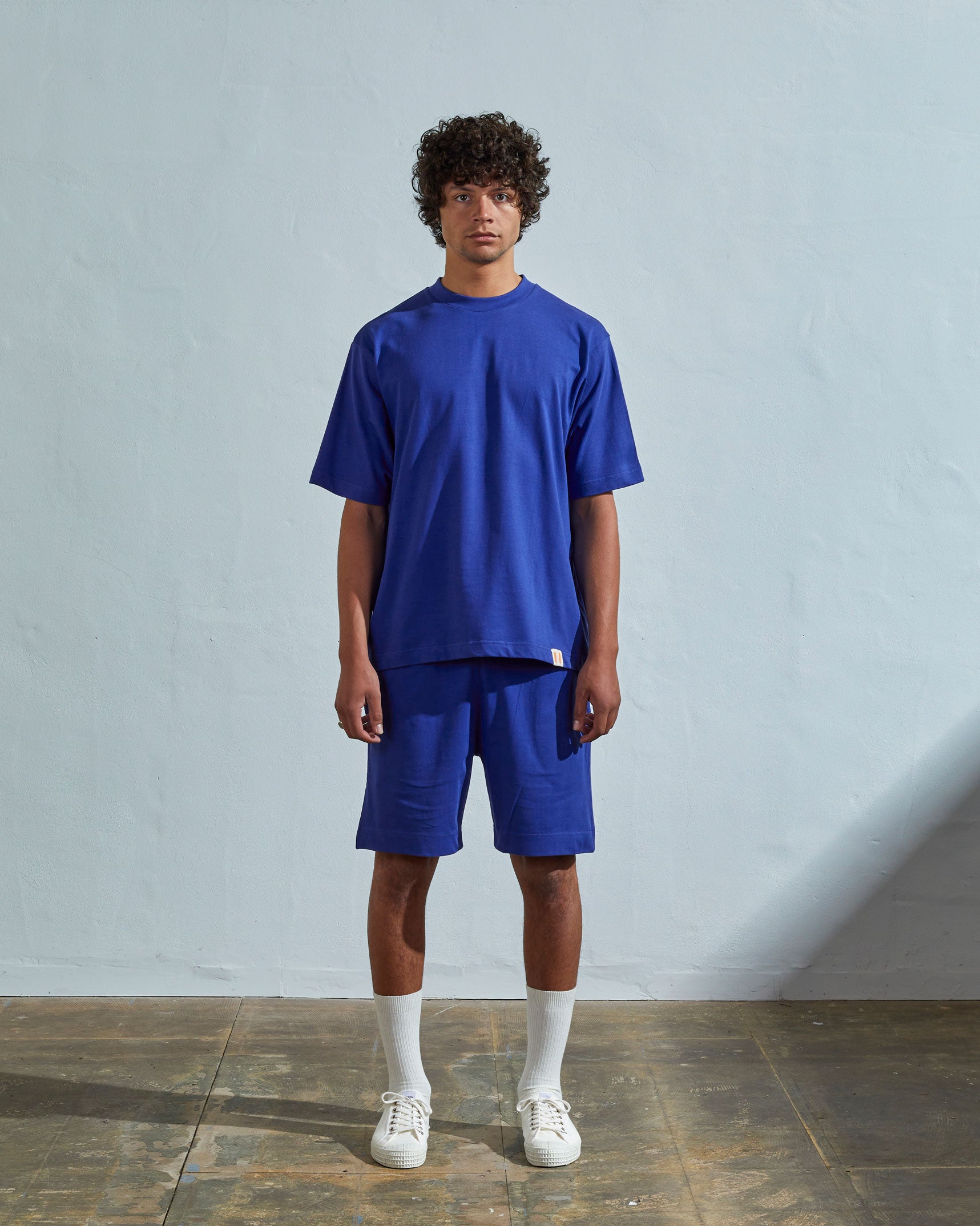 Full-length front view of model wearing ultra blue organic cotton #7008 oversized jersey T-shirt by Uskees paired with matching shorts.