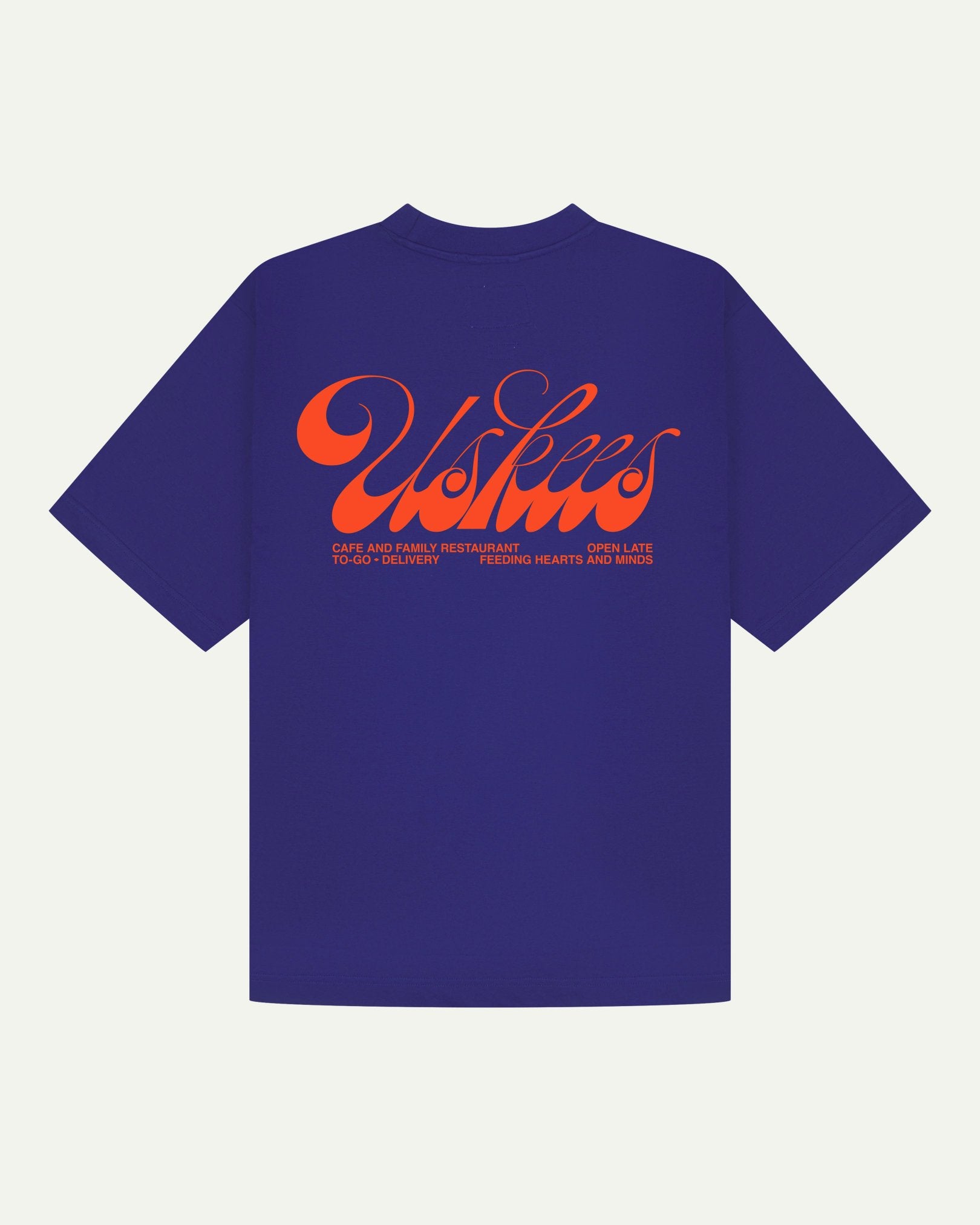 Back flat view of oversized ultra blue organic cotton Uskees short-sleeved T-shirt showing the loose silhouette. Spanning the back is the large, bright orange 'diner' logo.