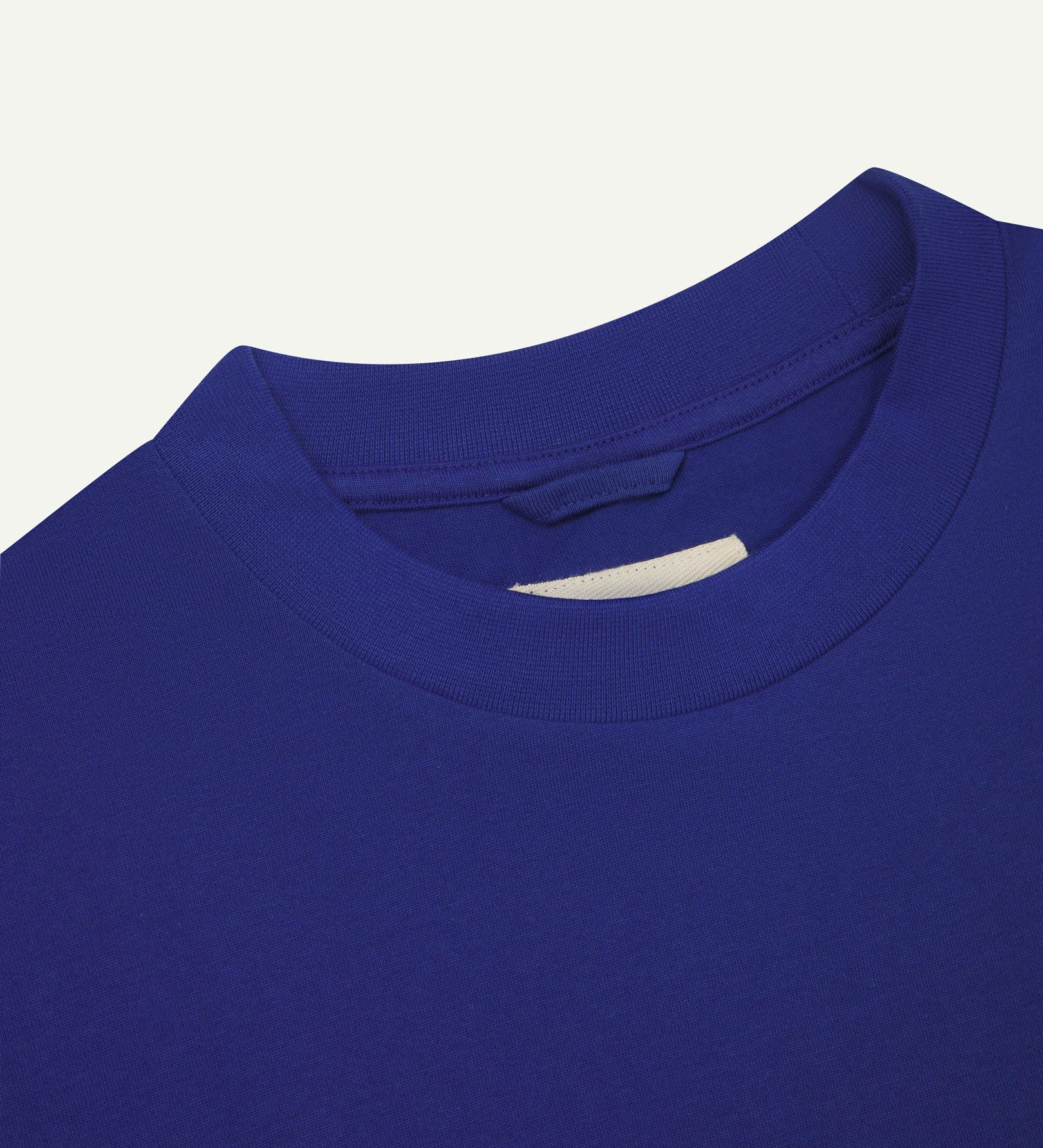 Neckline close-up of ultra blue organic cotton oversized T-shirt showing hanging loop and Uskees branding label.