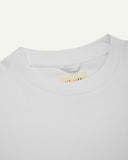 Neckline close-up of white organic cotton oversized T-shirt showing hanging loop and Uskees branding label.