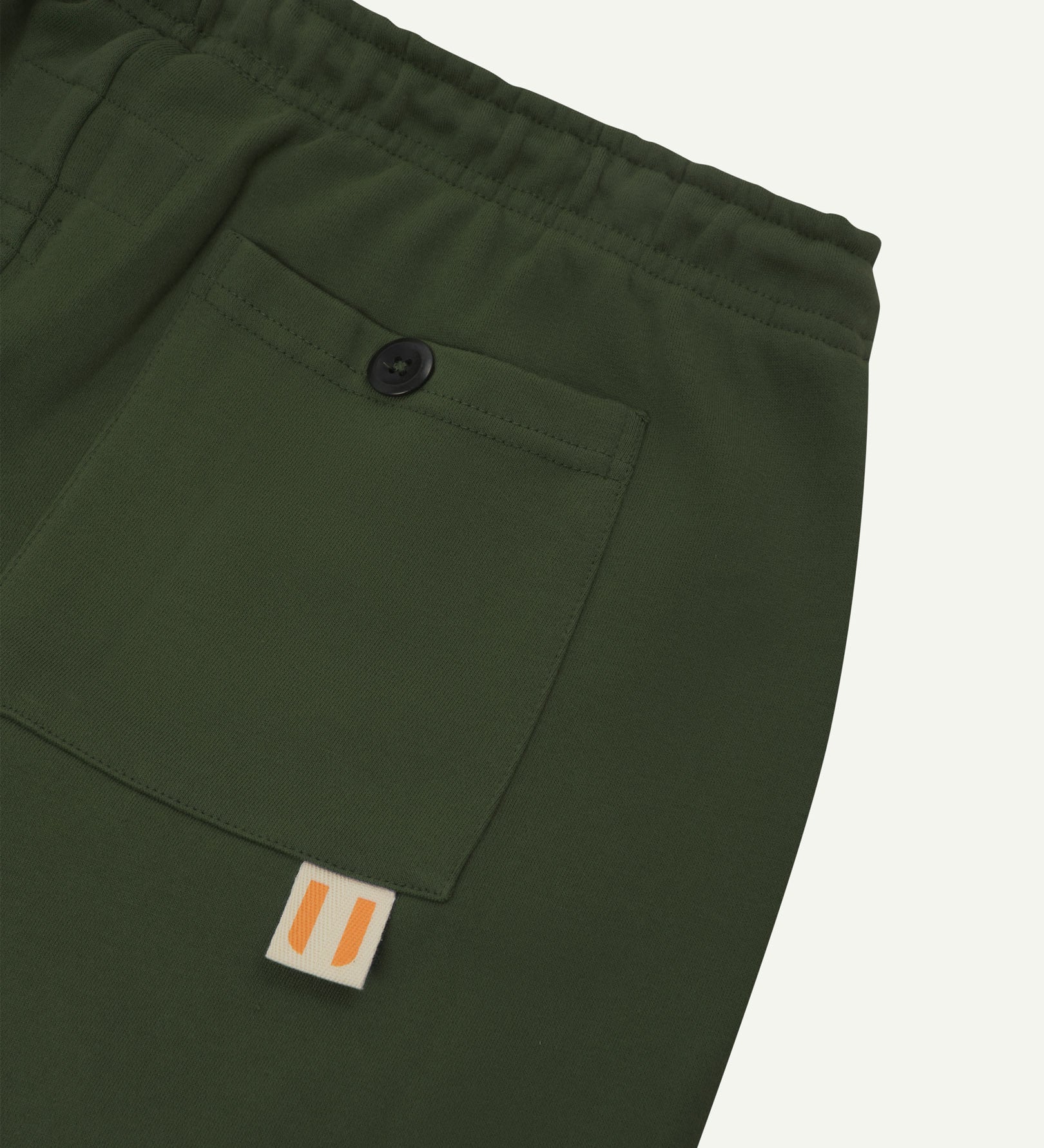 Back close view of organic cotton joggers by Uskees showing the buttoned back pocket and logo label.