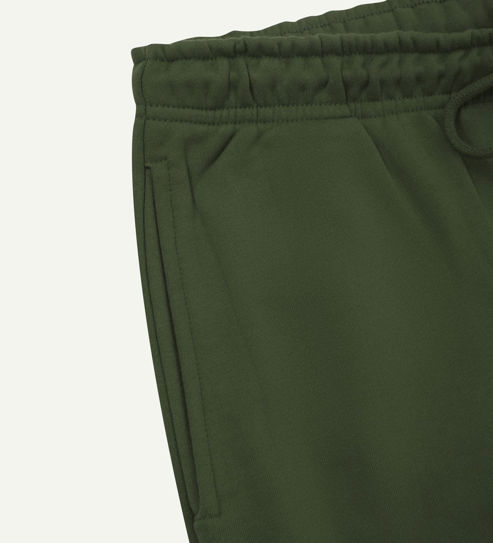 Close up view of organic cotton joggers in coriander-green showing the side pocket and drawstring waist.