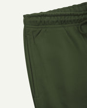 Close up view of organic cotton joggers in coriander-green showing the side pocket and drawstring waist.