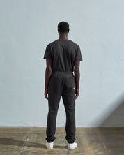 Full-length reverse view of model wearing Uskees  #7009 faded-black organic cotton joggers paired with matching Uskees t-shirt.