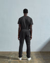 Full-length reverse view of model wearing Uskees  #7009 faded-black organic cotton joggers paired with matching Uskees t-shirt.