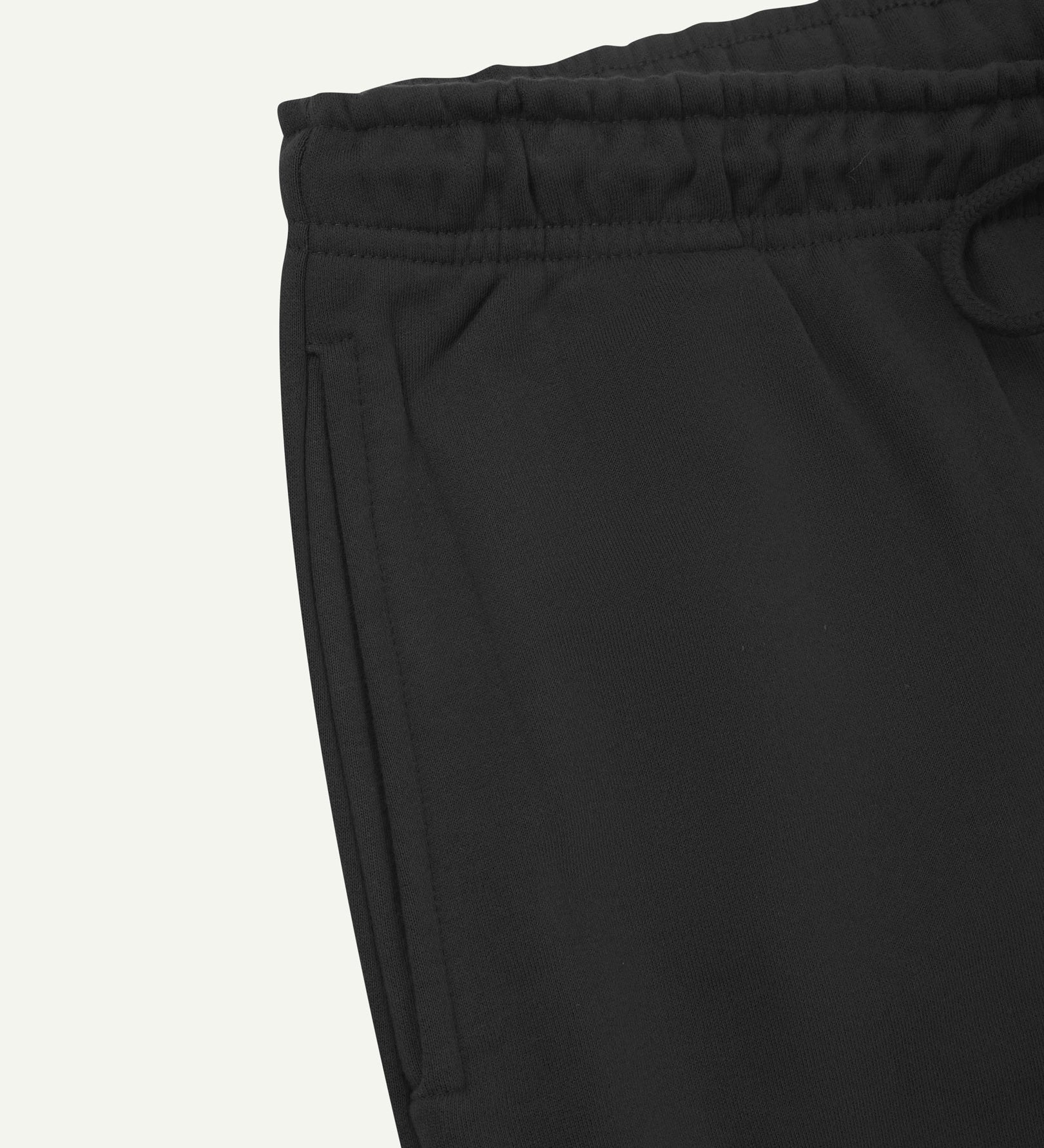 Close up view of organic cotton joggers in faded black showing the side pocket and drawstring waist.