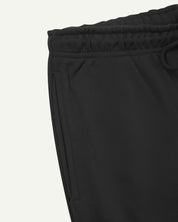 Close up view of organic cotton joggers in faded black showing the side pocket and drawstring waist.