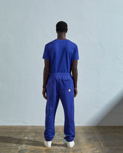 Full-length reverse view of model wearing Uskees 7009 ultra-blue organic cotton joggers paired with matching Uskees t-shirt.