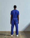 Full-length reverse view of model wearing Uskees 7009 ultra-blue organic cotton joggers paired with matching Uskees t-shirt.