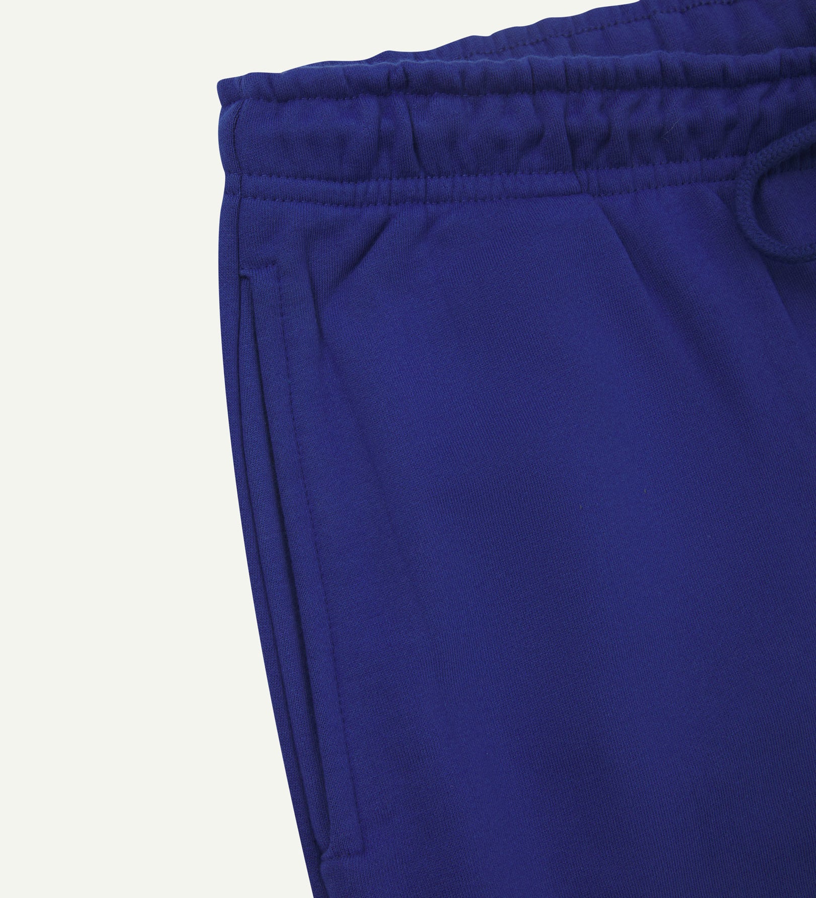 Close up view of organic cotton joggers in ultra-blue showing the side pocket and drawstring waist.