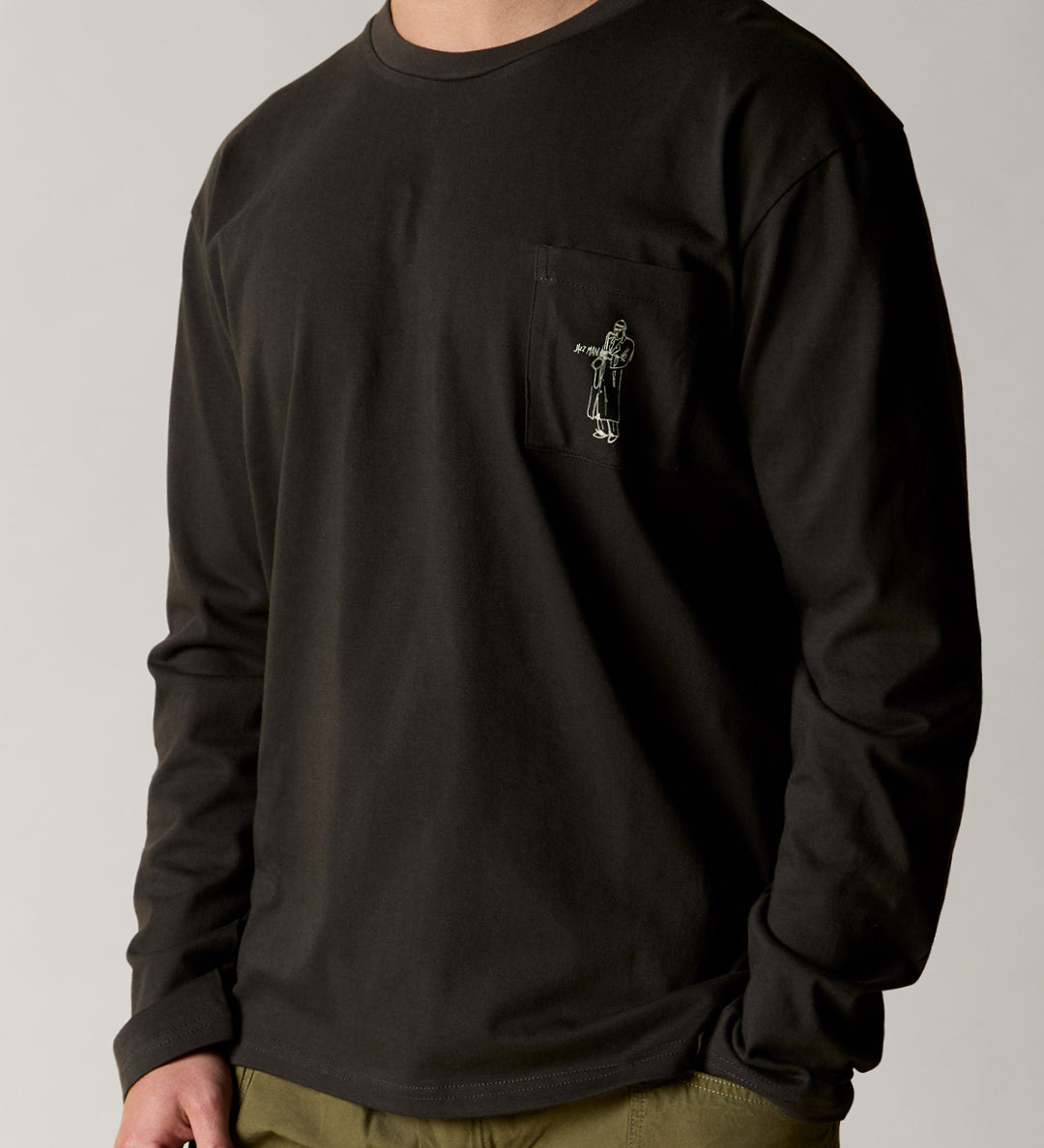 Front view wearing the uskees men's 'jazz man' long-sleeve tee in faded black demonstrating the loose, relaxed fit and highlighting the white 'Jazz Man' logo on the breast pocket.