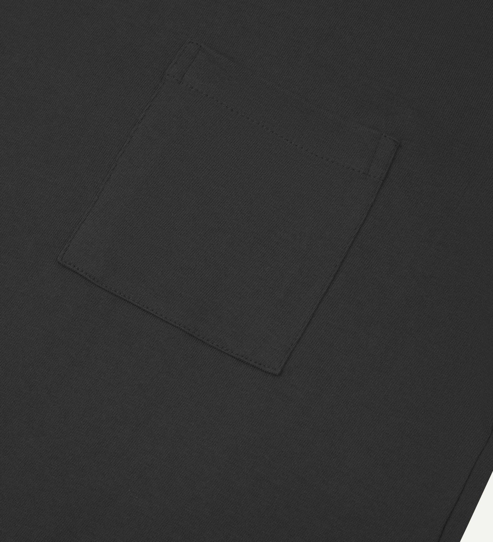 Sleeve and neckline close-up of Uskees faded black organic cotton long-sleeved T-shirt with focus on breast pocket.