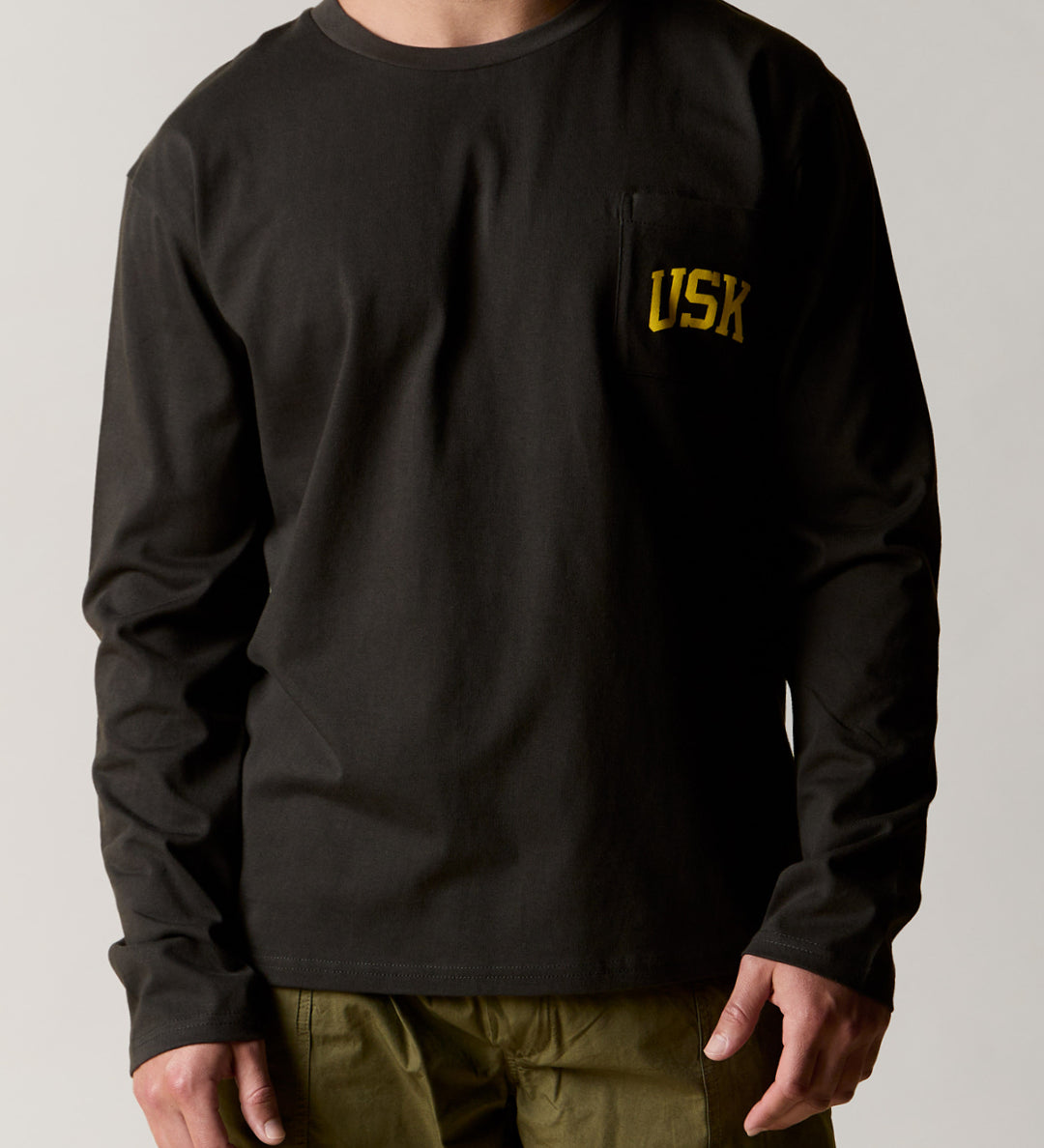 Front view wearing the faded black organic cotton signature long sleeve T-shirt for men, demonstrating the loose, relaxed fit.