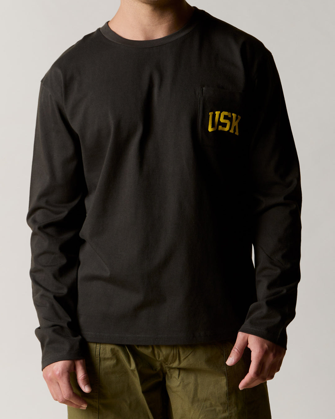 Front view wearing the faded black organic cotton signature long sleeve T-shirt for men, demonstrating the loose, relaxed fit.