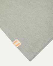 Closer look at the hem of the grey marl organic cotton long sleeve T-shirt showing texture of the medium weight organic cotton jersey and the small square Uskees branding tag.