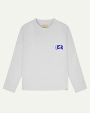 Full flat view of white organic cotton signature long sleeve T-shirt for men, showing the varsity inspired 'USK' logo in blue on the chest pocket, and the Uskees branding labels on the neck and hem.