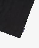 View of hemline of Uskees black cotton vest with focus on breathable, non-see-through fabric and blue 'USKEES' logo tab.