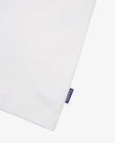 View of hemline of Uskees white cotton vest with focus on breathable, non-see-through fabric and blue 'USKEES' logo tab.