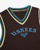 Front close view of a brown sleeveless sweater vest with 'USKEES' branding on the front in blue.