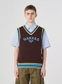 Front view of a male model wearing a brown sleeveless sweater vest with 'USKEES' branding on a light gray background.