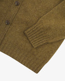 Close up view of Uskees olive-green lambswool Harris cardigan with focus on the ribbed detailing on hem, cuffs and pockets.