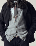 Torso view of model wearing stone-grey Harris cardigan with focus on corozo buttons and soft lambswool weave.